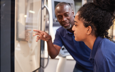 Engineer Showing Apprentice How To Use CNC Tool Making Machine