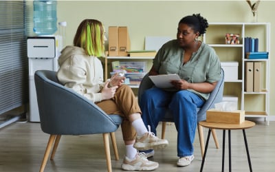Woman social worker talking to teenage girl at office